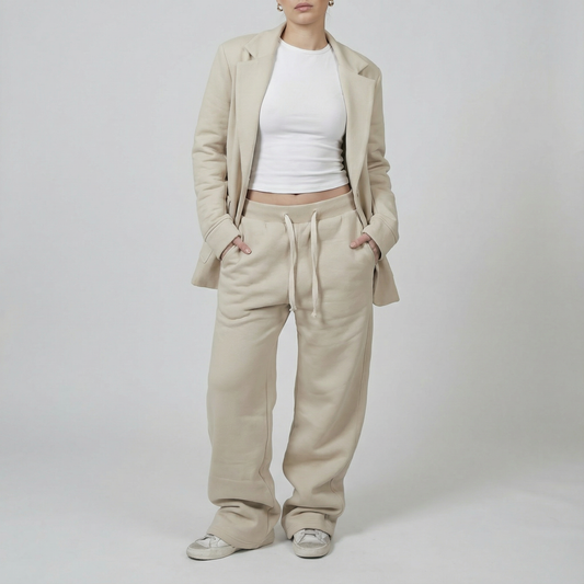 Person wearing a beige suit with a white top on a plain background