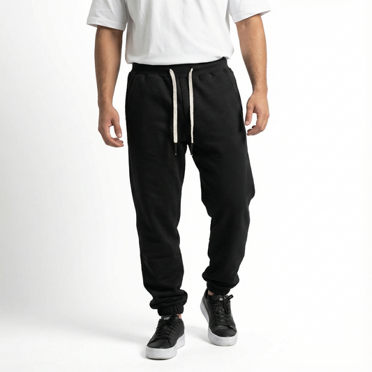 Person wearing black jogger pants with white drawstring on a white background