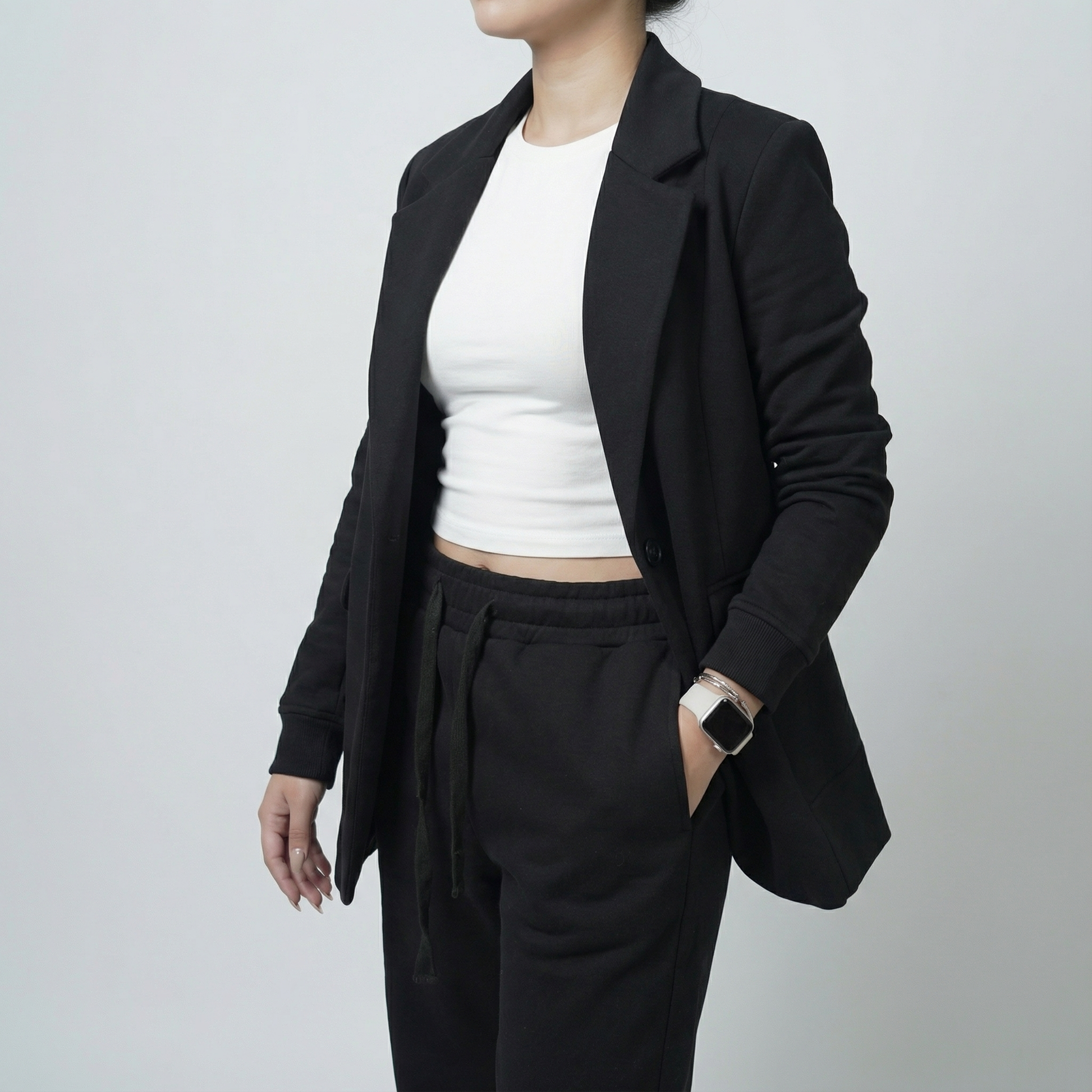 Person wearing a black blazer and black pants with a white top on a plain background