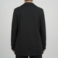Black coat worn by a person on a plain background