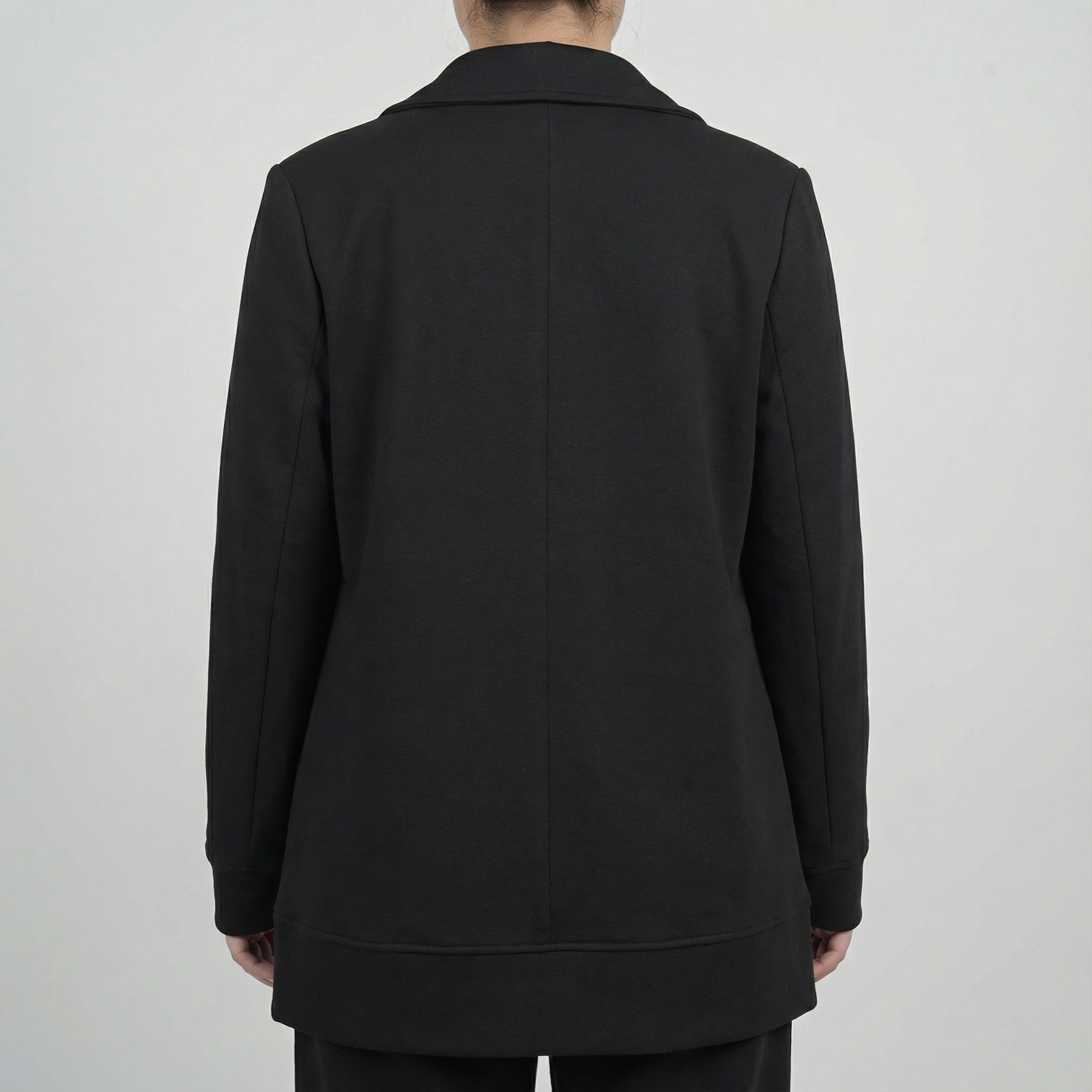 Black coat worn by a person on a plain background