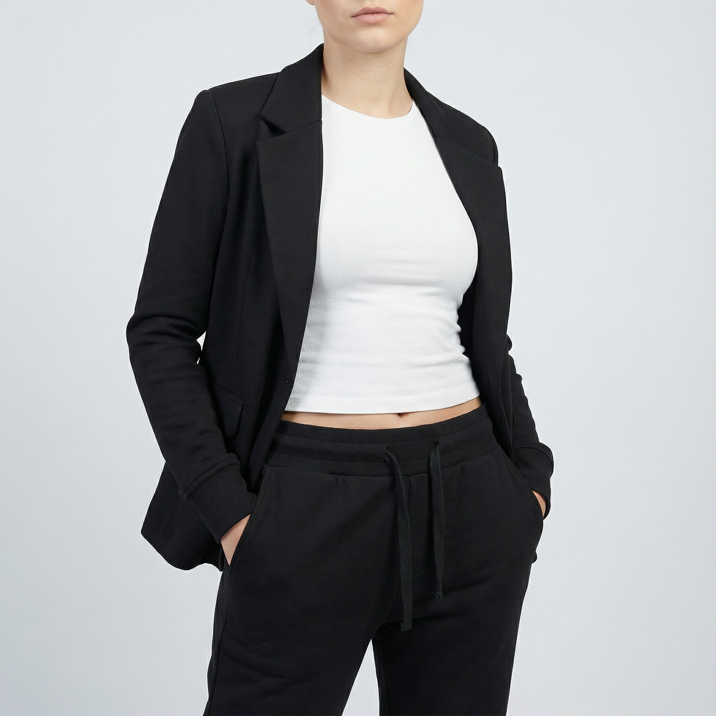 Person wearing a black blazer, white top, and black pants on a light gray background
