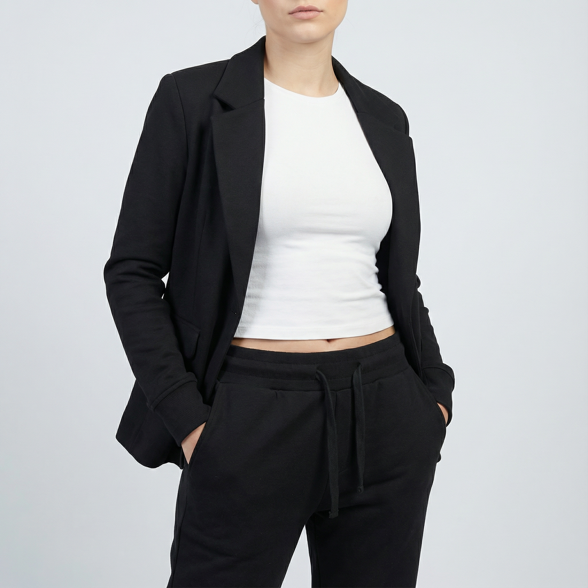 Person wearing a black blazer, white top, and black pants on a light gray background