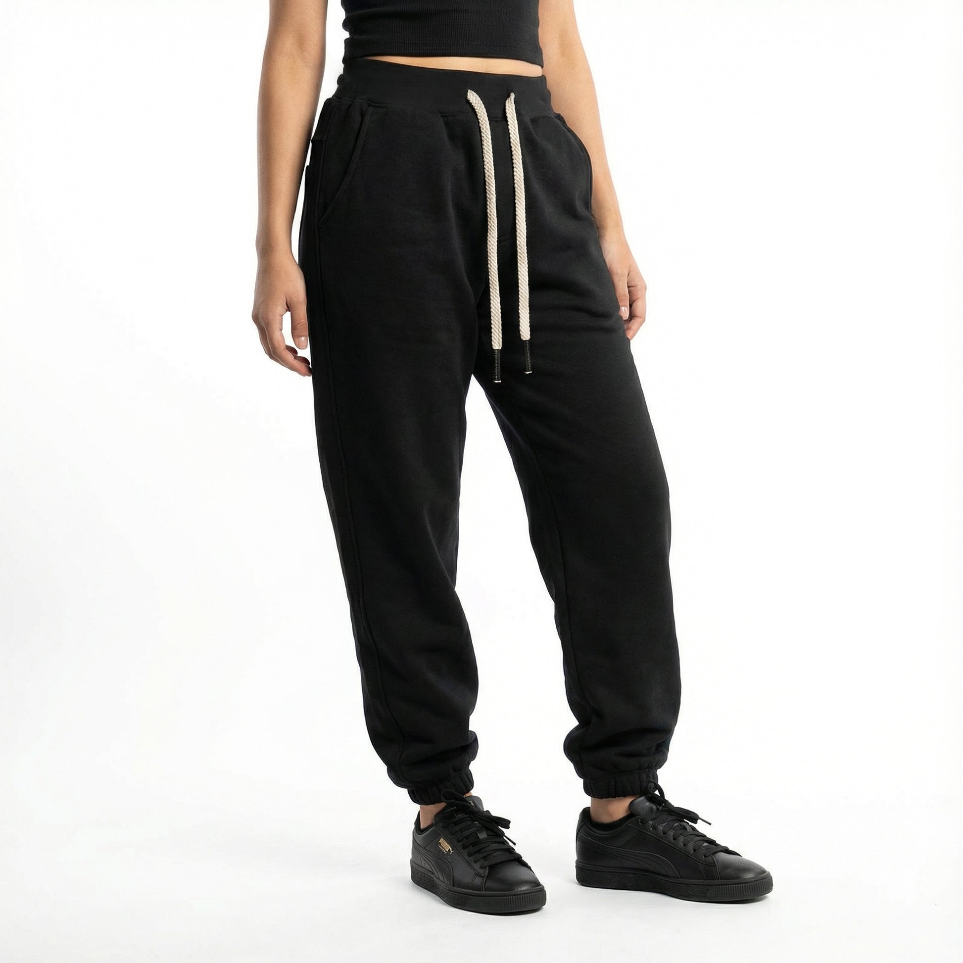 Person wearing black jogger pants with a white stripe on a white background